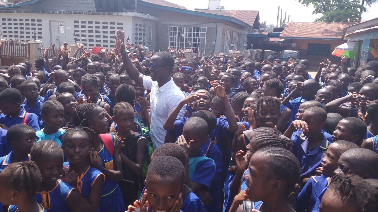 Abdulai surrounded by cheering pupils in blue uniforms